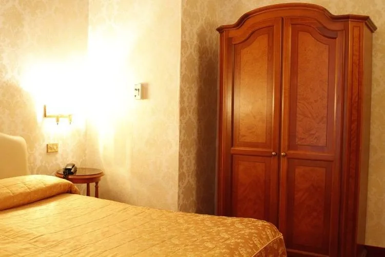 Representative hotel space: A bedroom with a bed beside a wooden wardrobe.