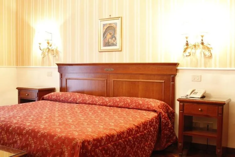 Representative hotel space: A bedroom with a large bed beneath a wooden headboard.