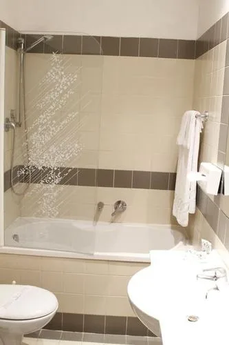 Representative hotel space: A tiled bathroom with a bathtub, shower, toilet, and sink.