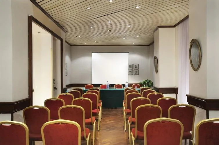 Representative hotel space: A small meeting room arranged with rows of red chairs facing a screen.