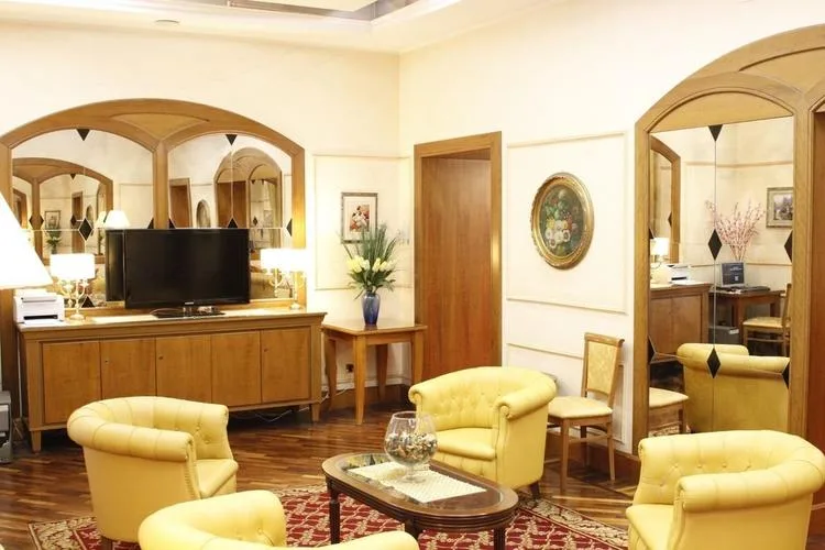 Representative hotel space: A furnished sitting room has yellow seating, wooden cabinetry, and large arched mirrors.