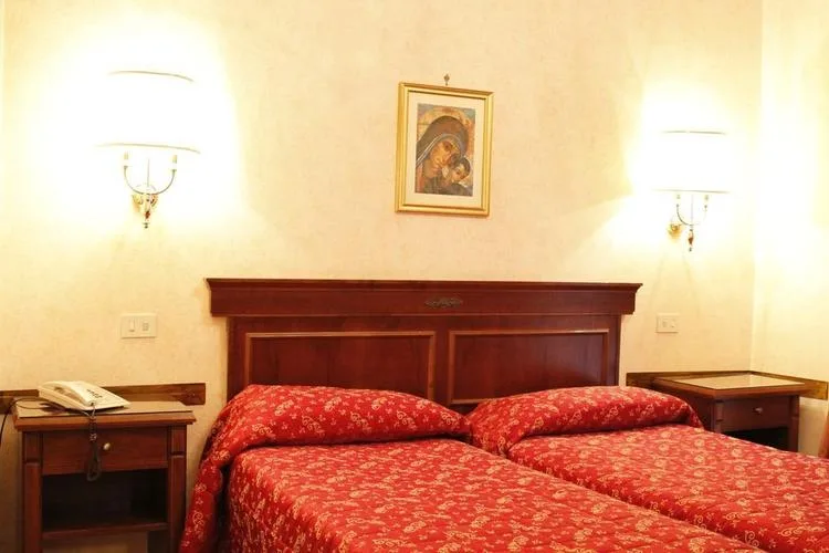 Representative hotel space: A bedroom with two beds beneath a dark wooden headboard and framed wall art.
