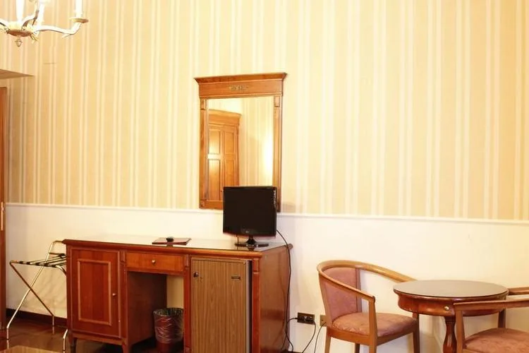 Representative hotel space: A furnished room with a wooden desk, television, and seating.