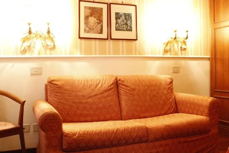 Representative hotel space: A patterned sofa sits against a wall decorated with framed pictures and lamps.
