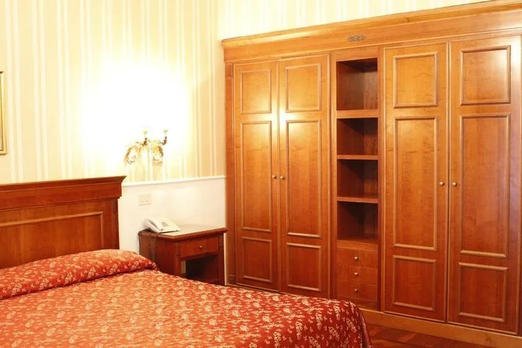 Representative hotel space: A bedroom with a patterned bedspread and a large wooden wardrobe.