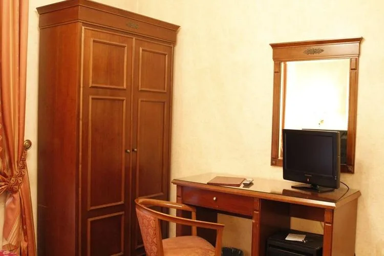 Representative hotel space: A bedroom workspace with a wooden desk, chair, wardrobe, and wall mirror.