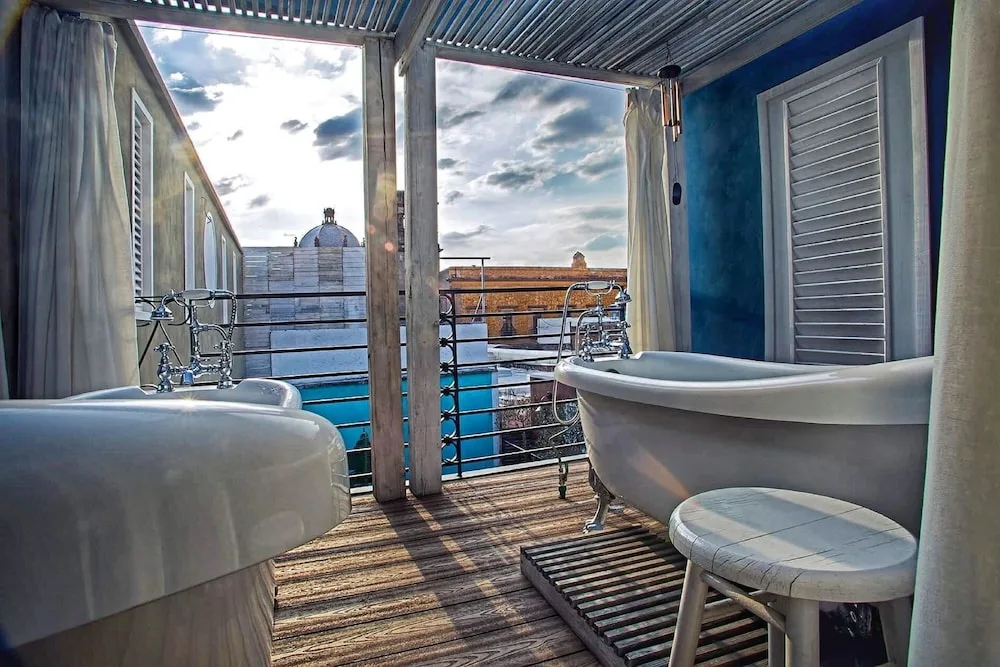 Espacio representativo del hotel: Un baño al aire libre con bañera y vistas al agua.