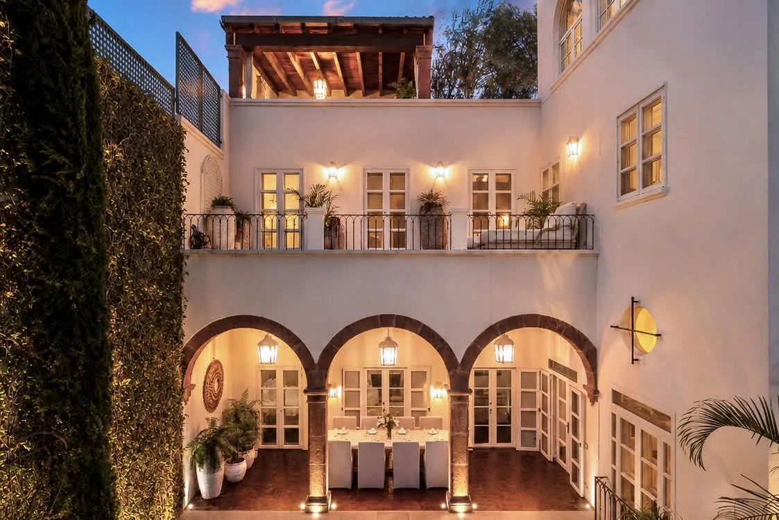 Un patio iluminado con arcos, balcones y plantas en macetas.