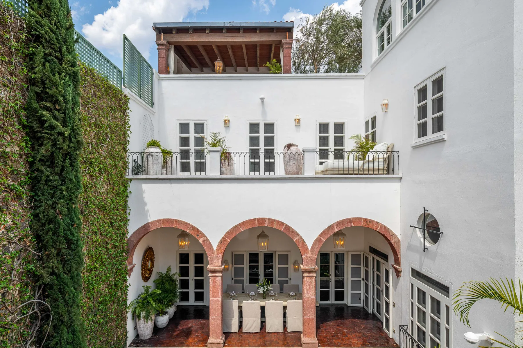 Un patio blanco con arcos, ventanas en la planta superior y un balcón.