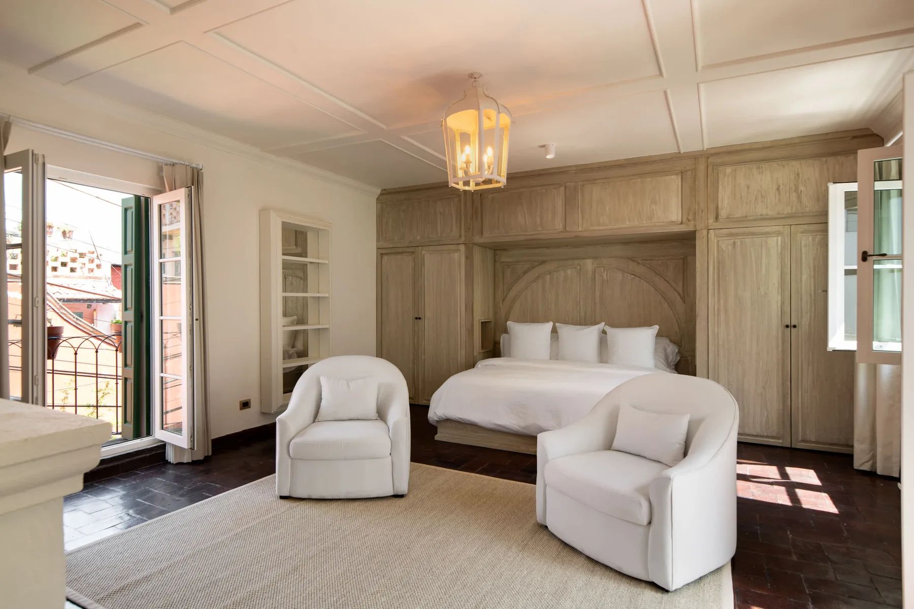 Un dormitorio con una cama, asientos blancos y armarios de madera empotrados.