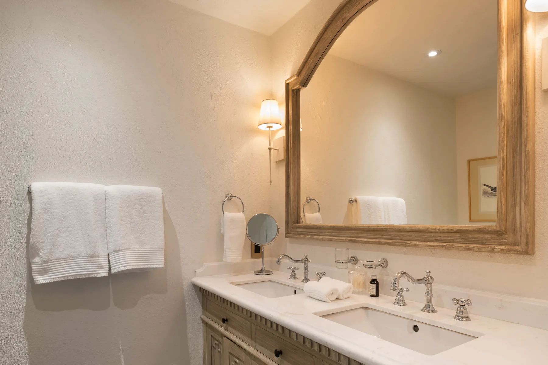 Un lavabo de baño con un espejo grande y toallas dobladas.
