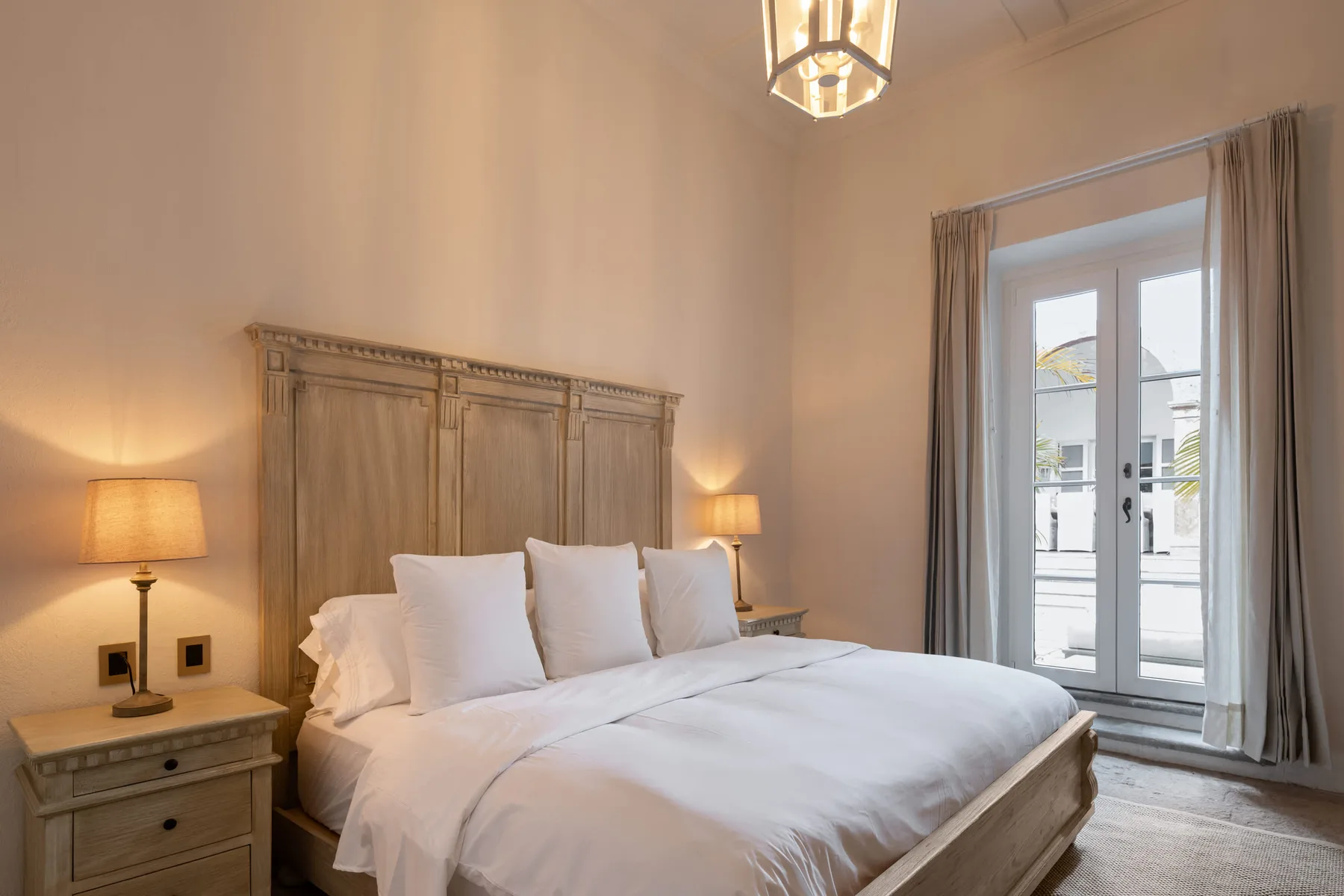 Un dormitorio con una cama grande, mesitas de noche y una puerta de cristal.