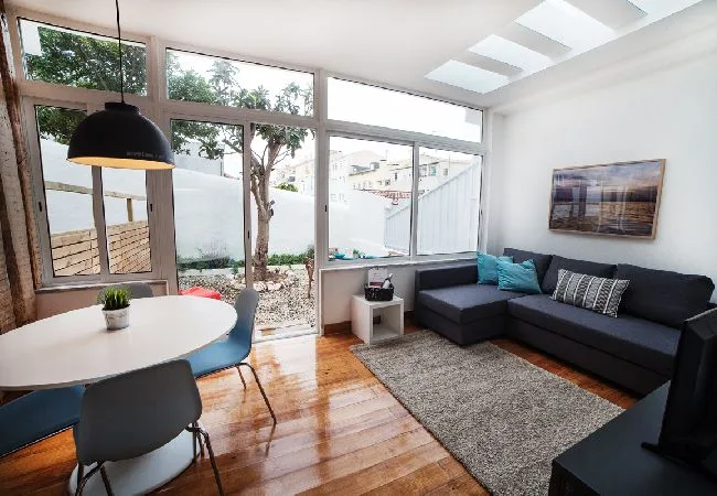 A bright living and dining area with a sectional sofa and large windows.