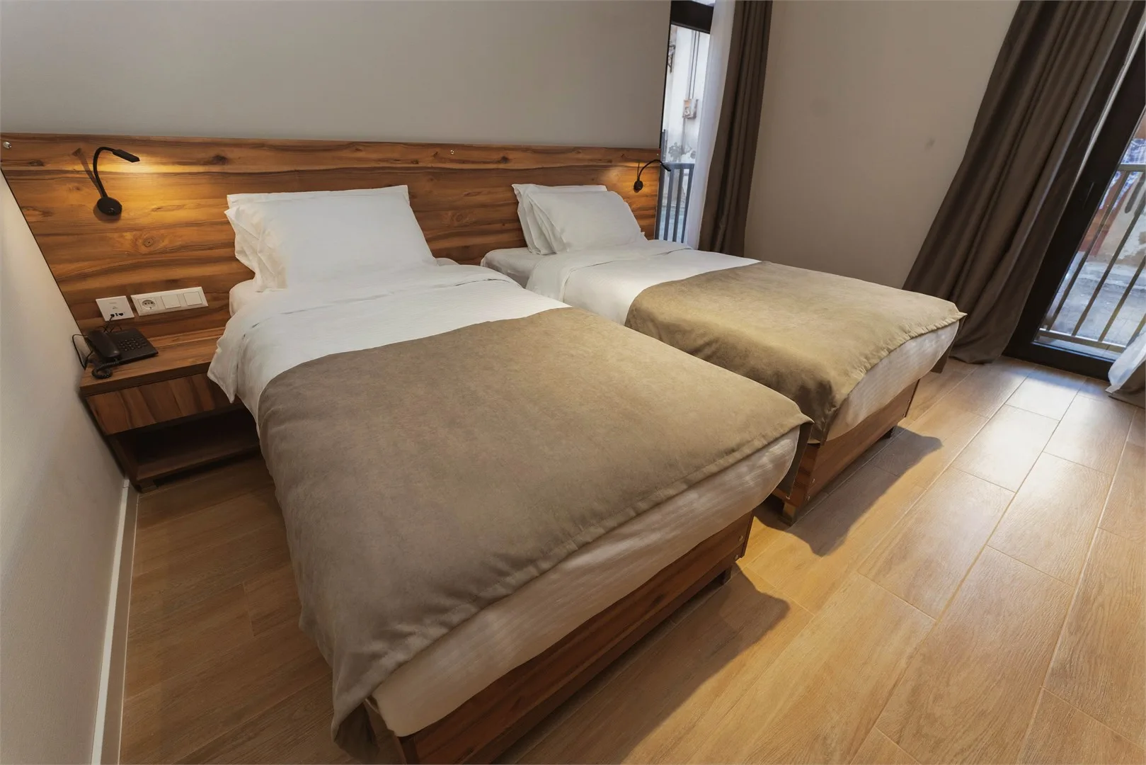 Representative hotel space: A bedroom with two beds beside tall windows.