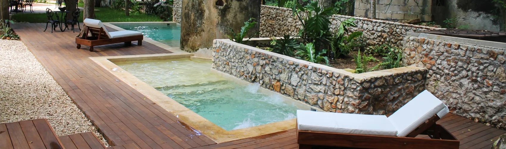 Representative hotel space: An outdoor pool area with lounge seating beside stone garden walls.