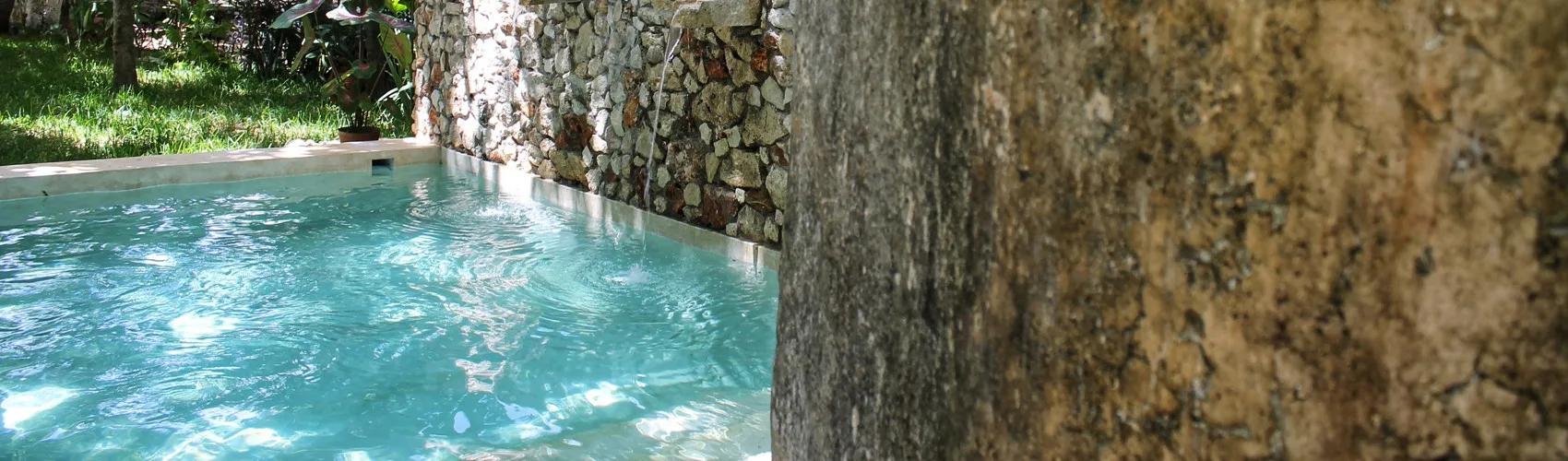 Representative hotel space: A small outdoor pool sits beside a stone wall and greenery.