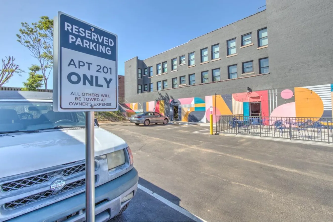 Zona común: Un estacionamiento junto a un mural colorido en un edificio de varias plantas.