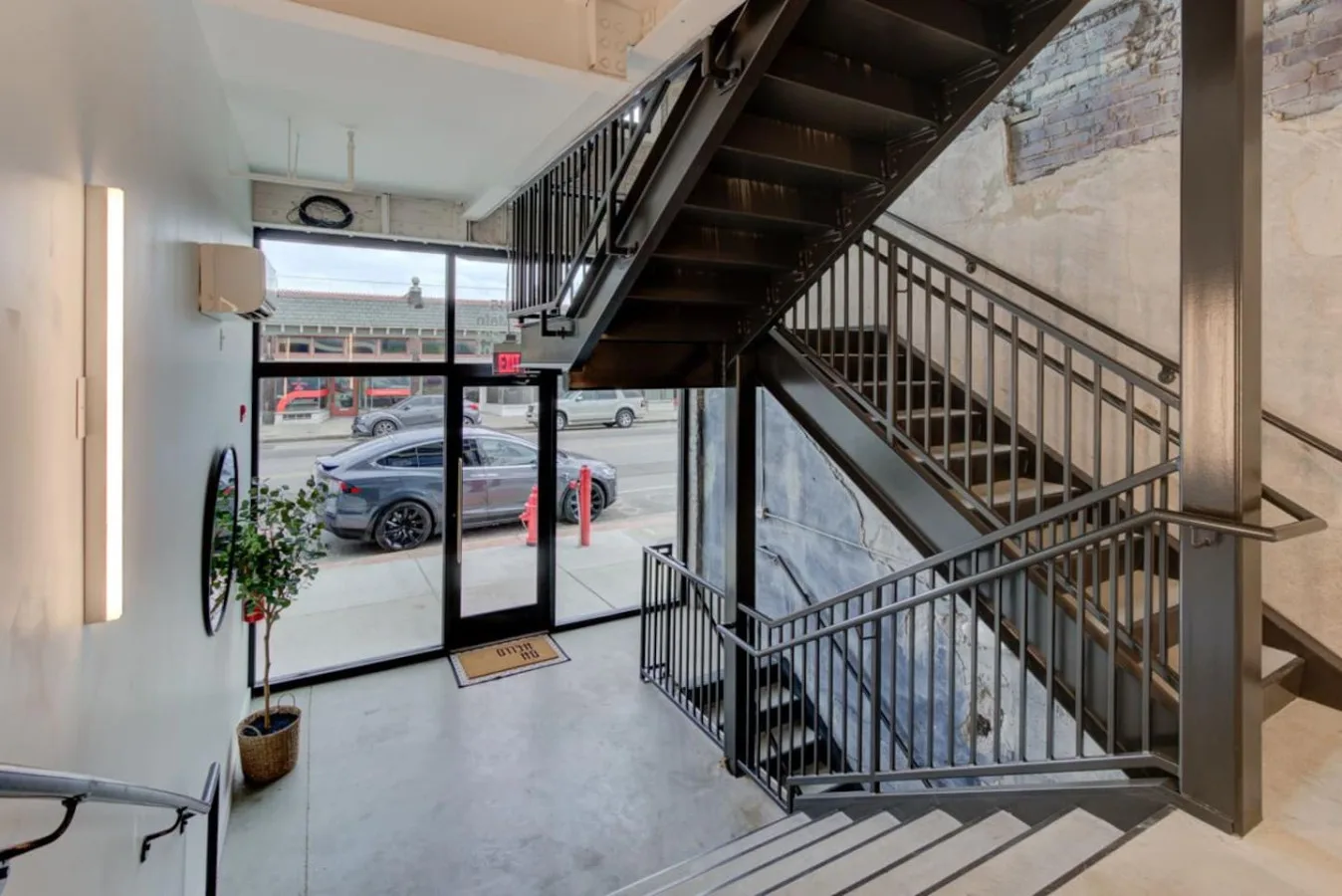 Zona común: Una escalera interior con barandillas metálicas y una entrada acristalada.