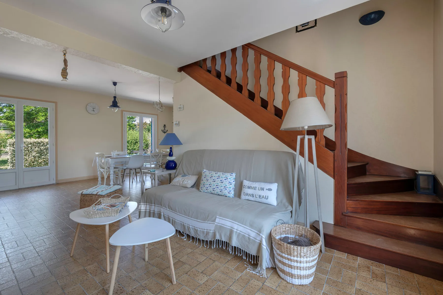 A living room with a gray sofa beneath a wooden staircase.
