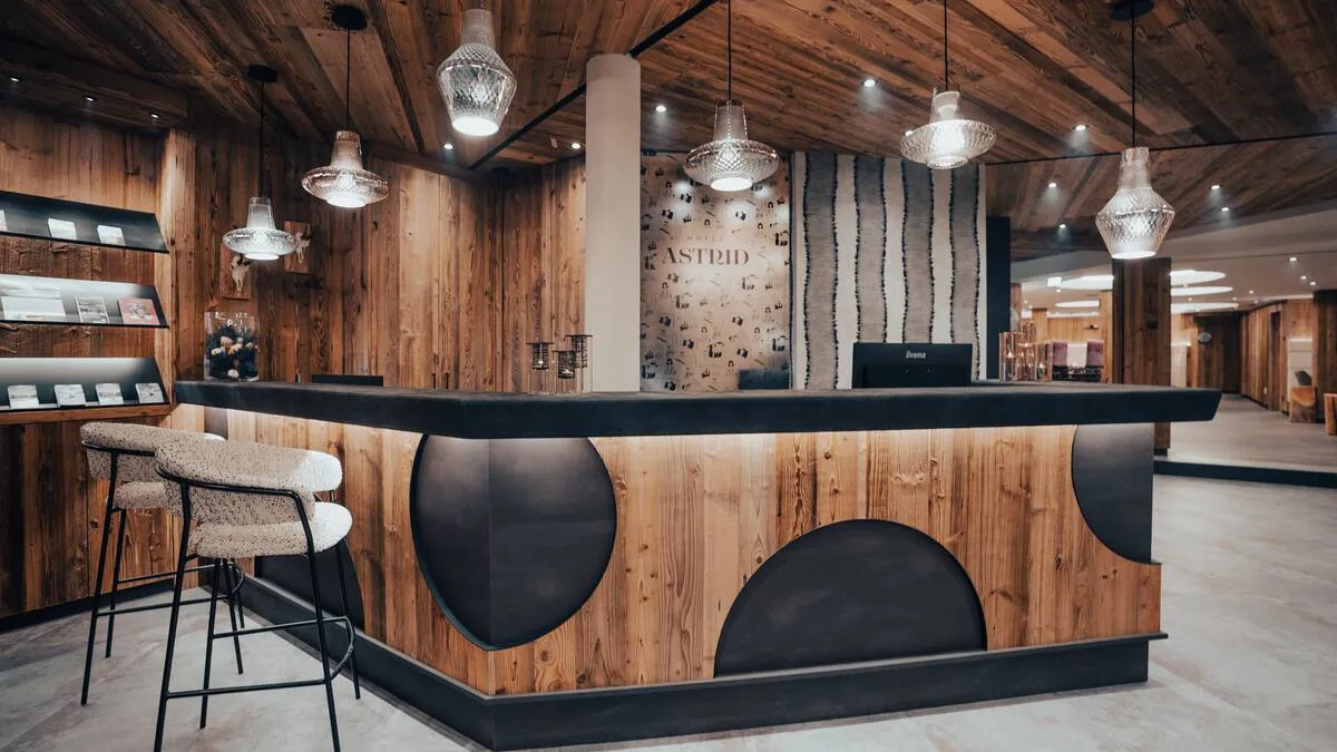 Espacio representativo del hotel: Un mostrador de recepción revestido de madera con taburetes bajo luces colgantes.