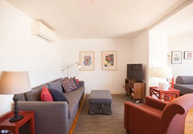 Una sala de estar con asientos, un televisor y cuadros enmarcados.