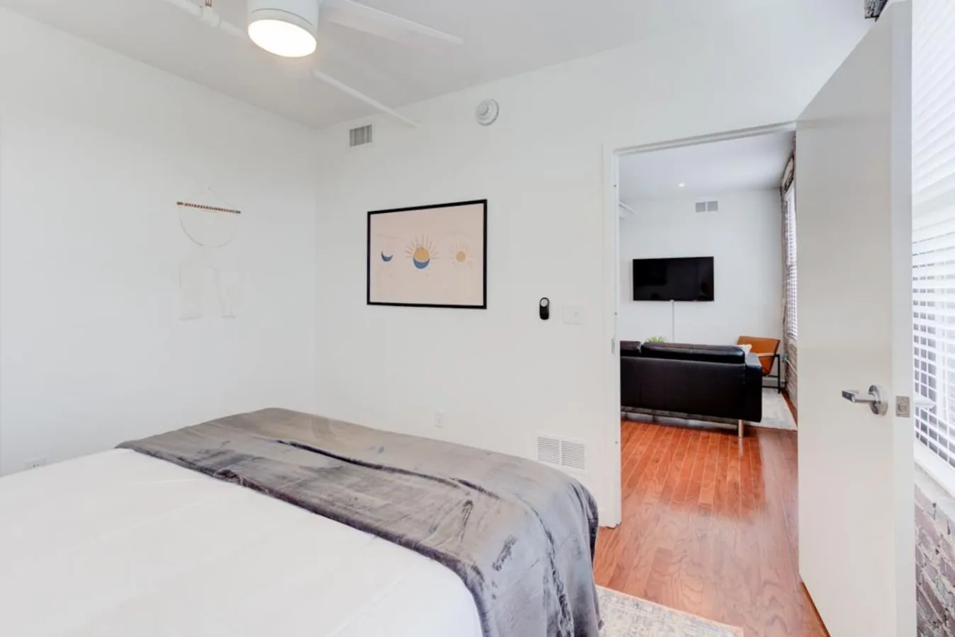 Un dormitorio luminoso con una cama y una puerta abierta a una zona de estar.