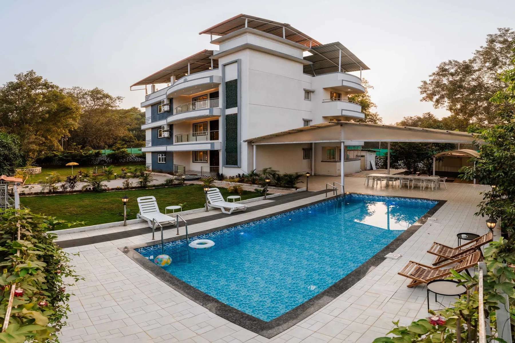 Un edificio moderno de varias plantas da a una piscina exterior con azulejos y un patio.