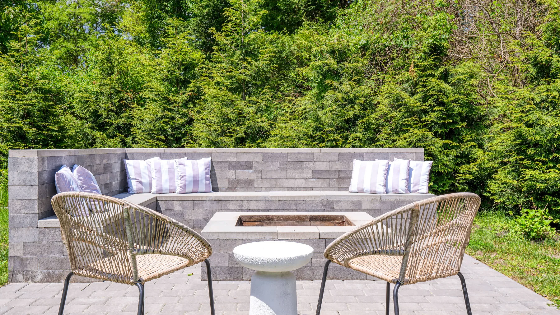 An outdoor patio seating area with two woven chairs around a low table.