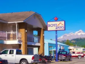 Representative hotel space: A roadside hotel building and sign stand beneath a clear sky with mountains beyond.