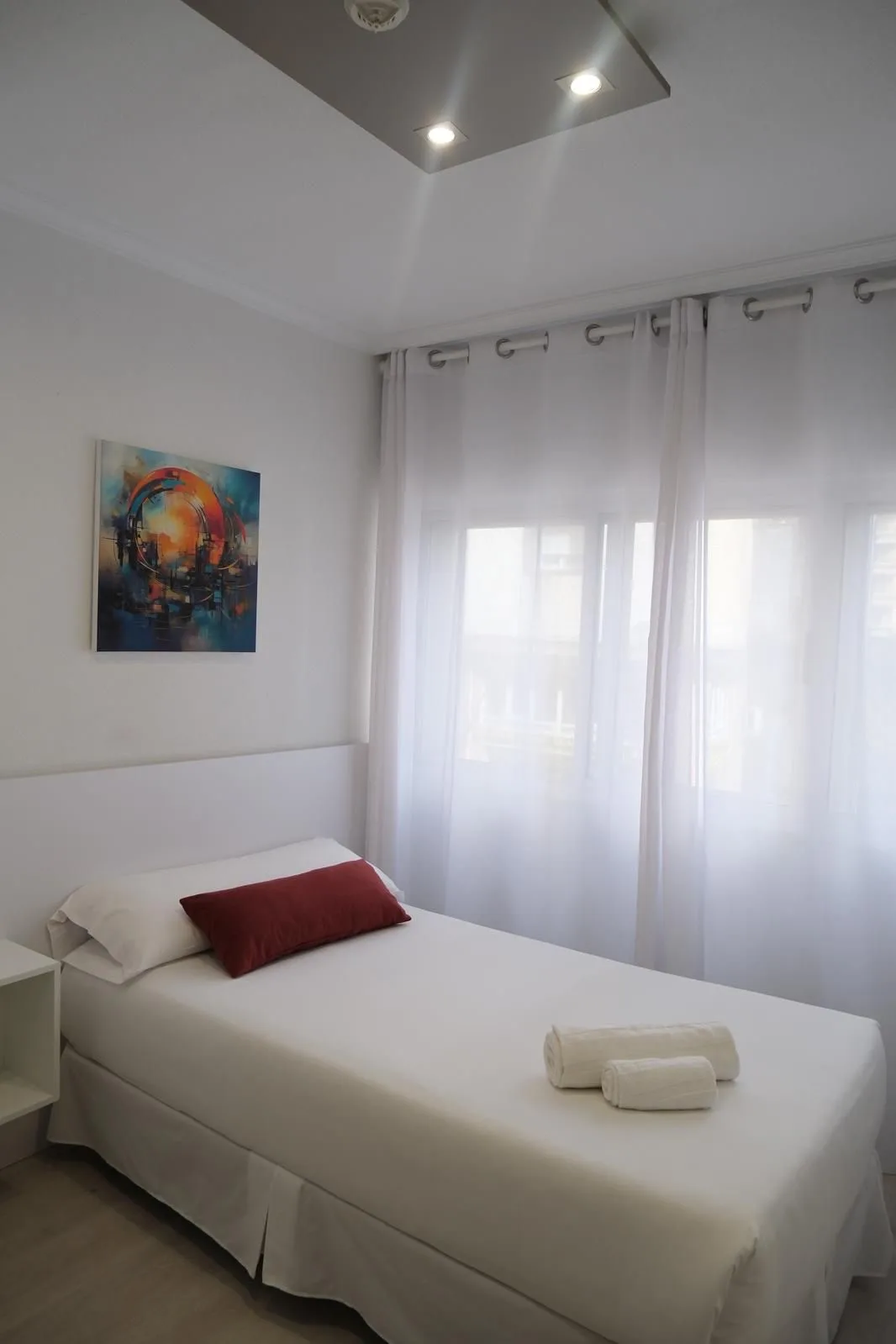 Espacio representativo del hotel: Un dormitorio luminoso con una cama bien arreglada y cortinas translúcidas.