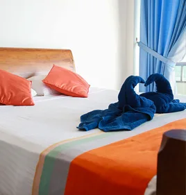 Representative hotel space: A bedroom with a neatly made bed and folded blue towels.