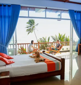 Representative hotel space: A bedroom with a large window overlooking a balcony and tropical greenery.