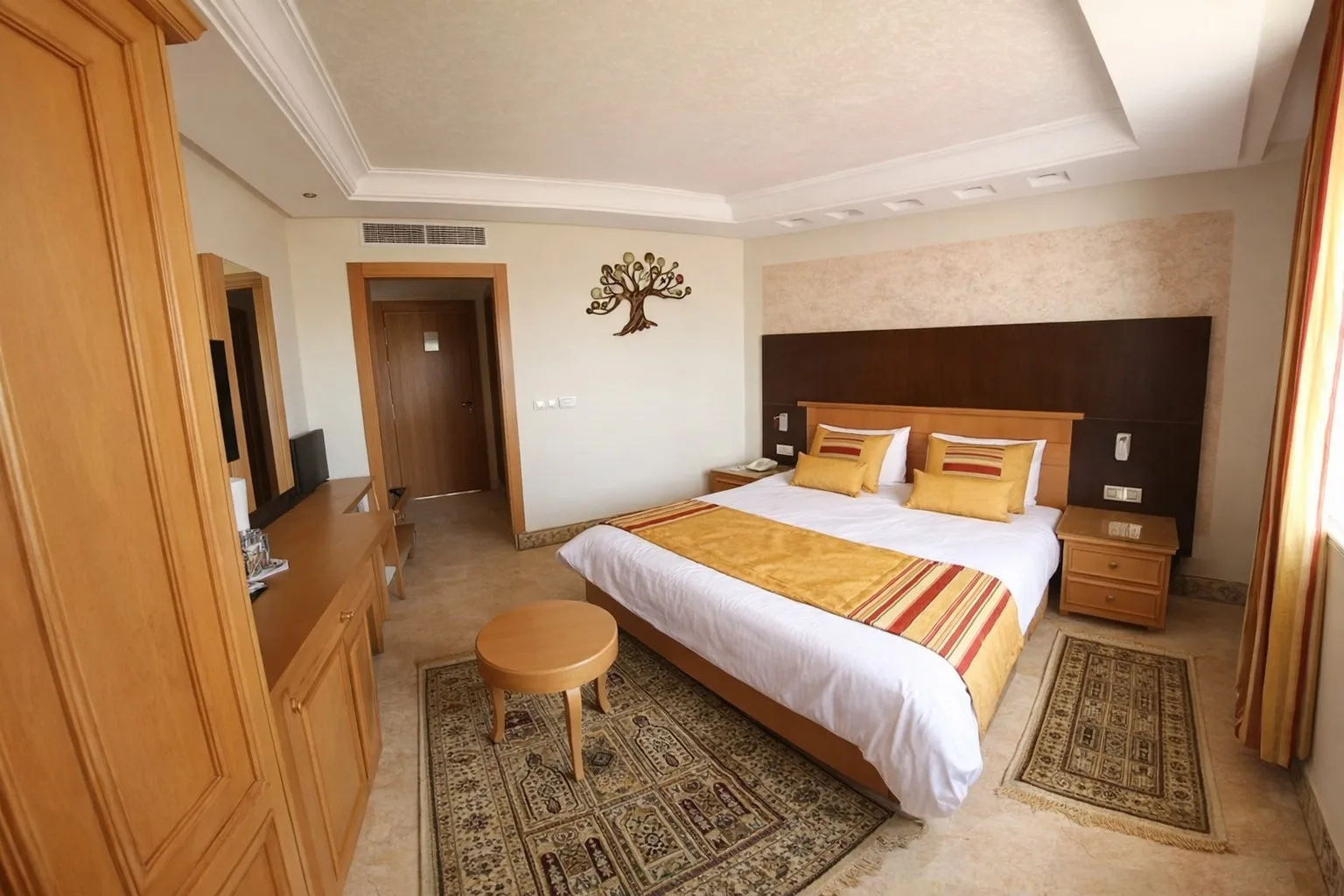 Espacio representativo del hotel: Un dormitorio con una cama doble, muebles de madera y alfombras estampadas.