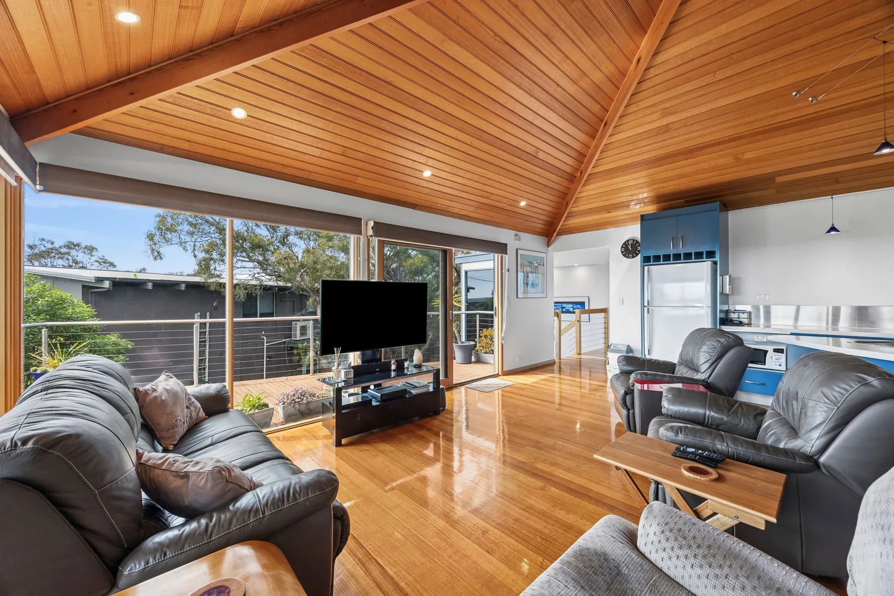 A living room with leather seating, a television, and large windows.