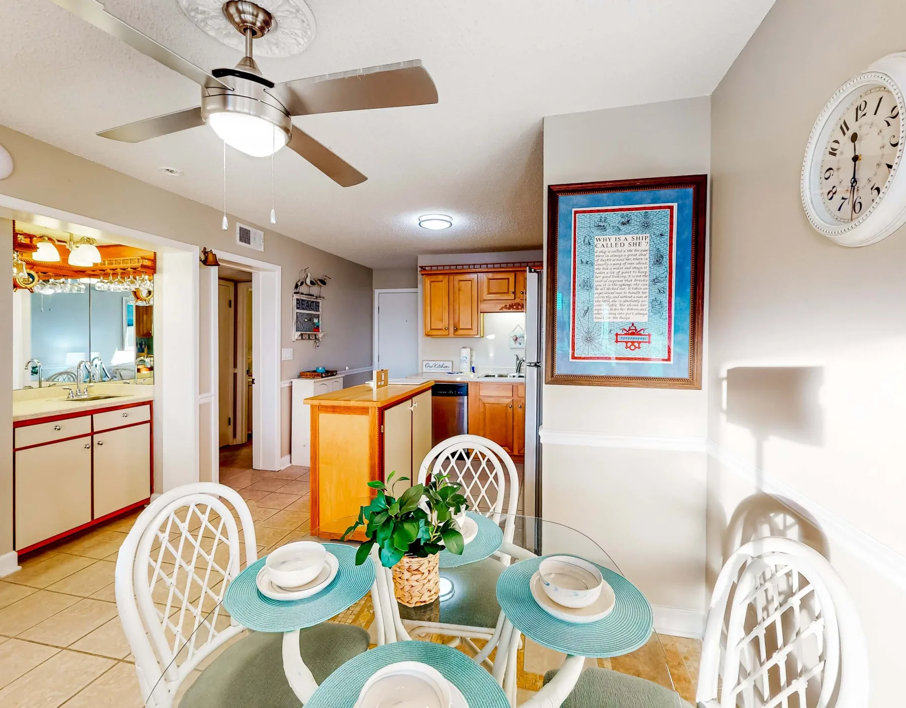 Un comedor se abre a una cocina, con una mesa de vidrio y puestos turquesa.
