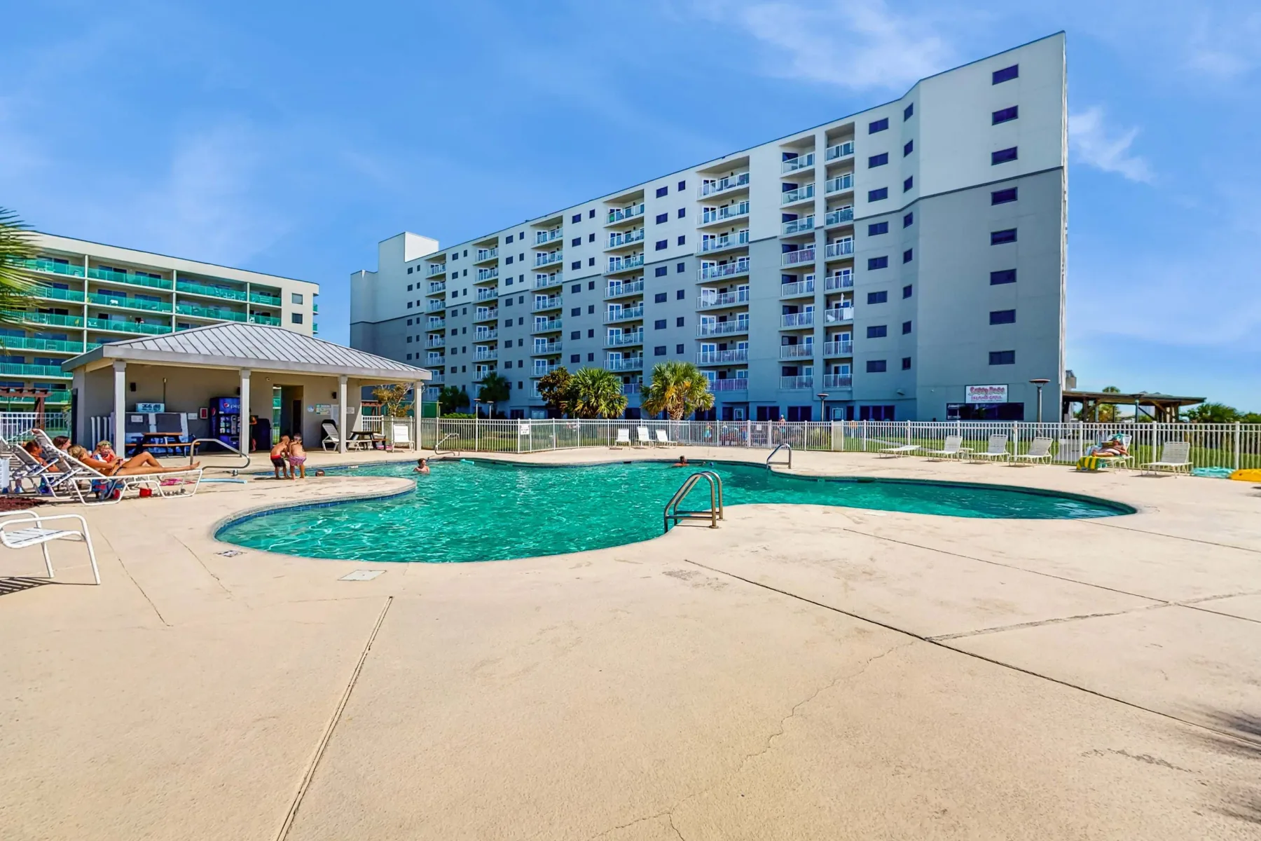 Zona común: Piscina al aire libre con una terraza pavimentada y edificios de apartamentos al fondo.