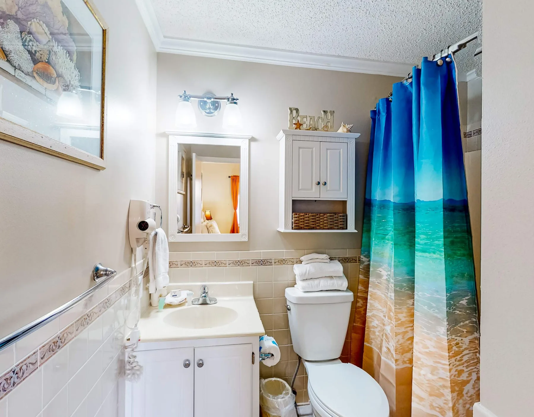 Un baño con lavabo, inodoro y cortina de ducha colorida.
