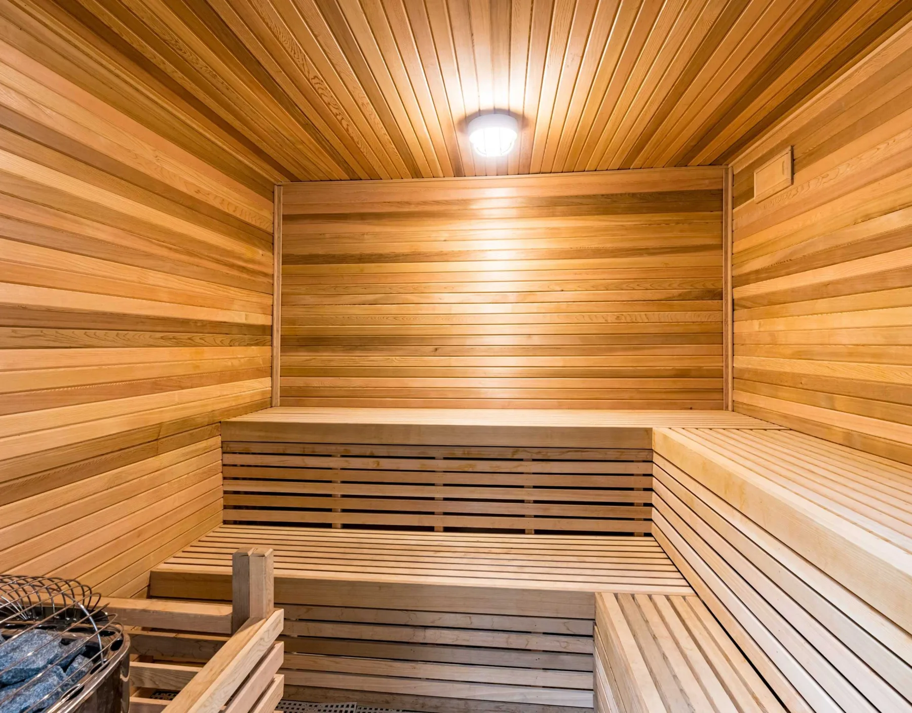 Zona común: Una sauna revestida de madera con asientos escalonados y un calentador.