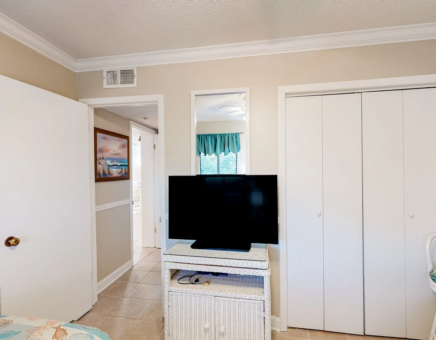 Dormitorio con un televisor sobre un mueble junto a un armario grande.