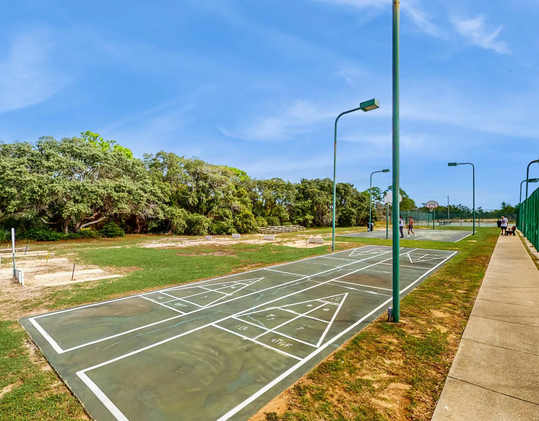 Zona común: Área recreativa al aire libre con canchas marcadas y un sendero pavimentado.