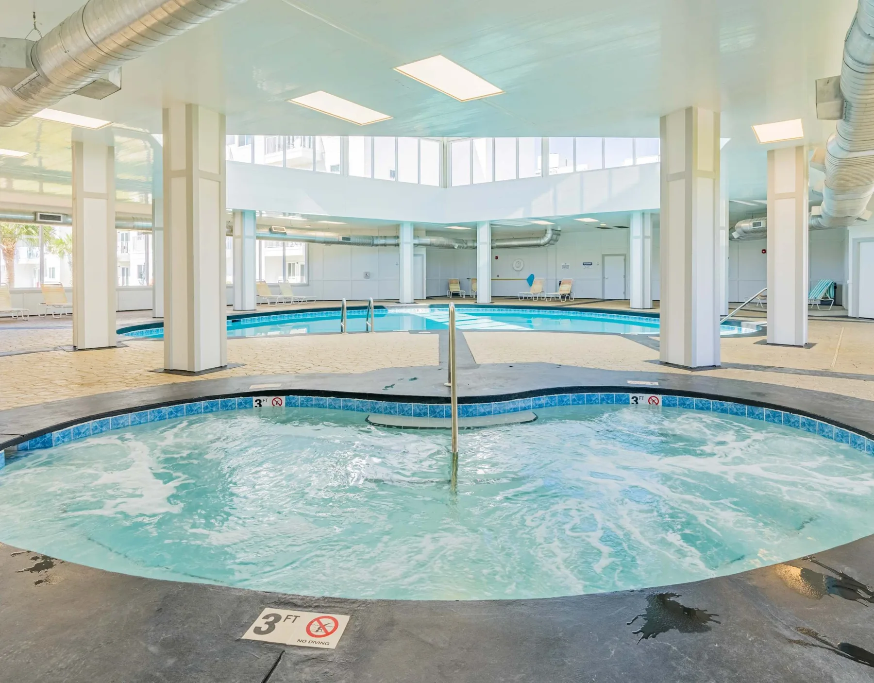 Zona común: Una piscina cubierta con una bañera de hidromasaje burbujeante en primer plano.