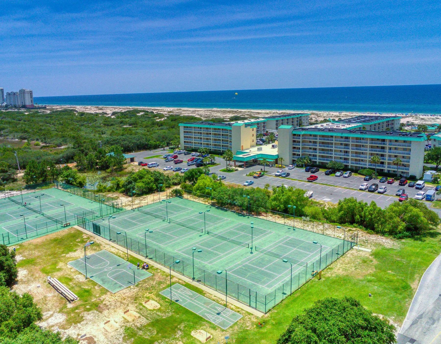 Zona común: Vista aérea de canchas de tenis junto a un hotel frente a la playa y el océano.