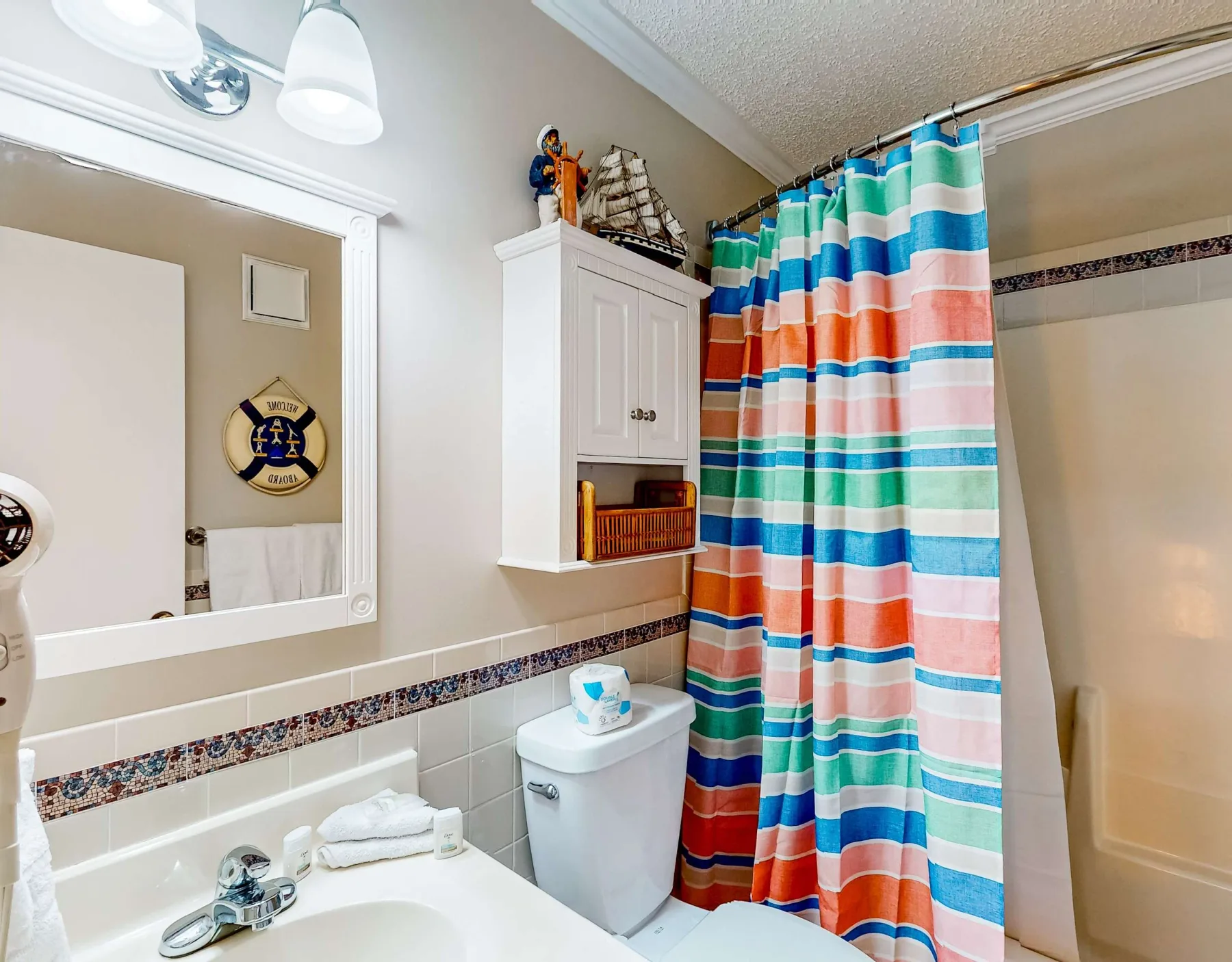 Un baño con una cortina de ducha de rayas coloridas y un lavabo.