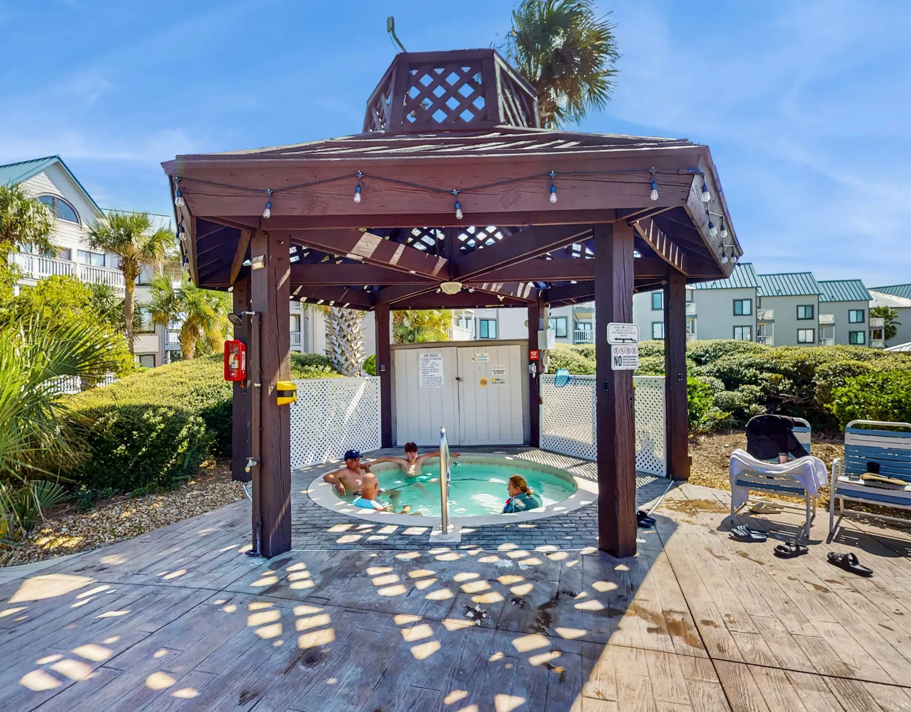 Zona común: Una piscina al aire libre está bajo una pérgola de madera en una terraza soleada.