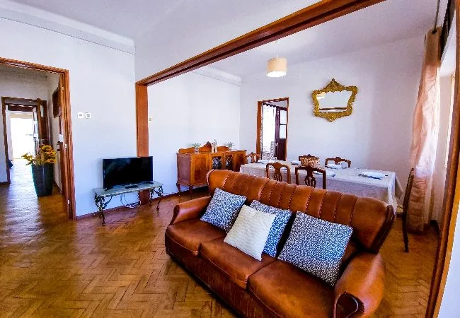 Sala de estar y comedor con asientos marrones, un televisor y una mesa de comedor.