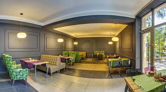 Espacio representativo del hotel: Un salón de hotel tiene asientos tapizados y mesas bajo lámparas colgantes.