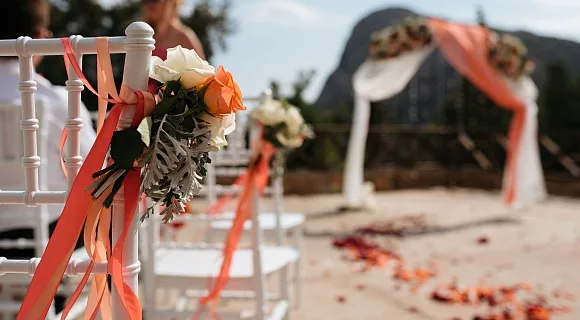 Espacio representativo del hotel: Los asientos de una ceremonia de boda al aire libre están decorados con flores y cintas.