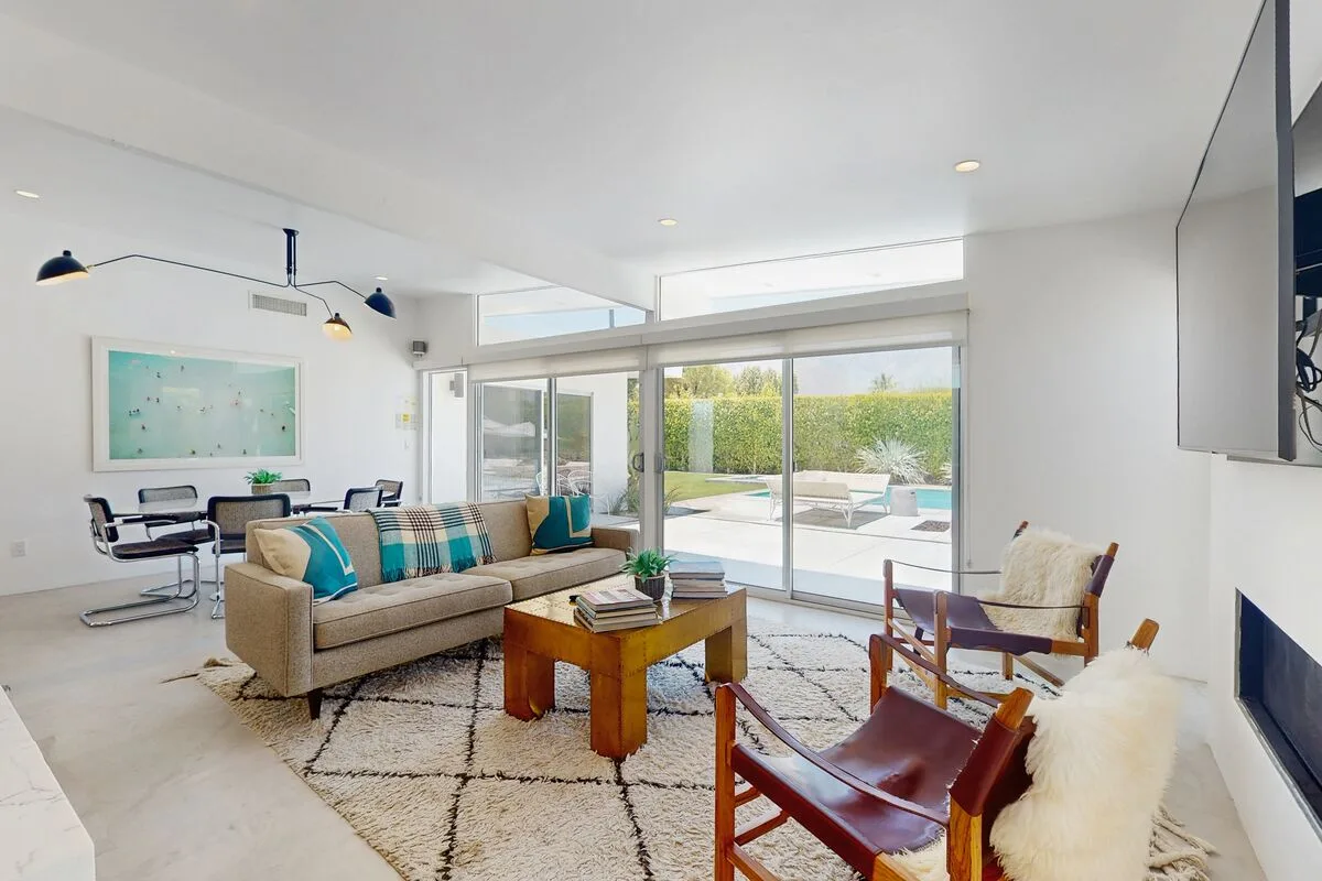 A bright living room with seating, a wooden coffee table, and large glass doors.