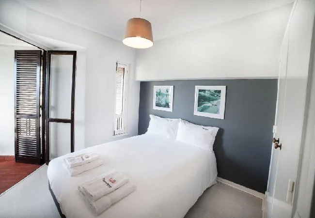 A bright bedroom with a white bed against a dark accent wall.