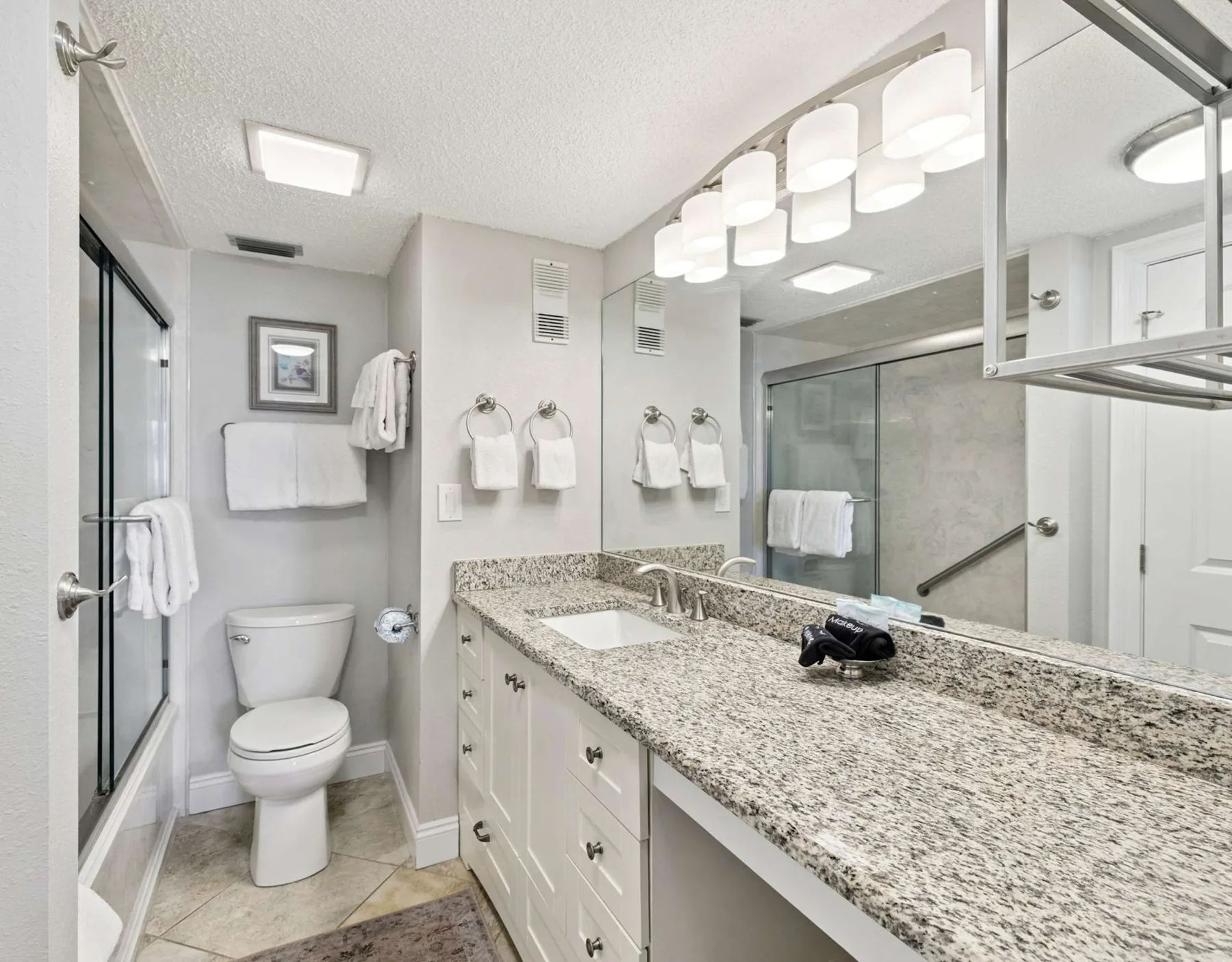 Un baño luminoso con un tocador largo, espejos y una ducha de vidrio.